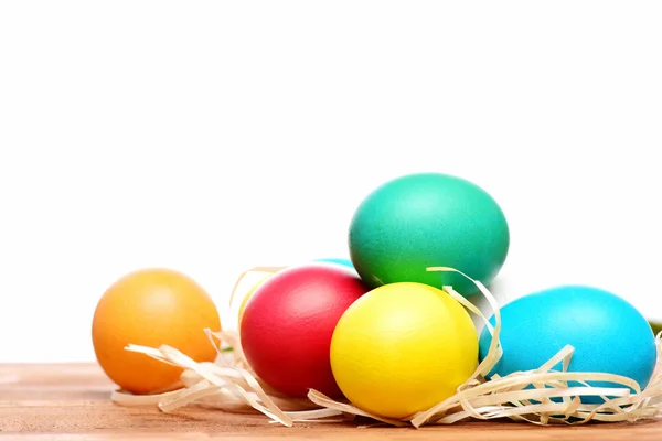 Huevos coloridos de Pascua pintados con nido de paja aislado en blanco — Foto de Stock
