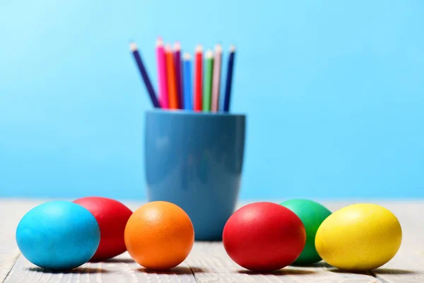Ovos de páscoa pintados e lápis colorido definido em copo azul — Fotografia de Stock