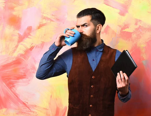 Skäggig brutal kaukasisk hipster med kaffekopp och svart anteckningsbok — Stockfoto