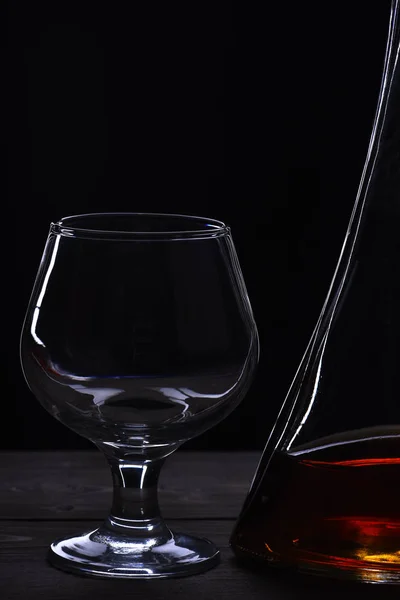 Glass and carafe with cognac, whiskey on black wooden table — Stock Photo, Image