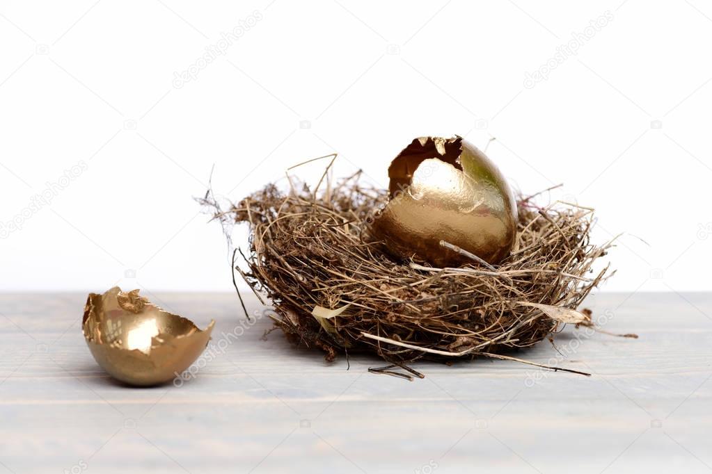 broken easter golden eggs with shell in bird nest