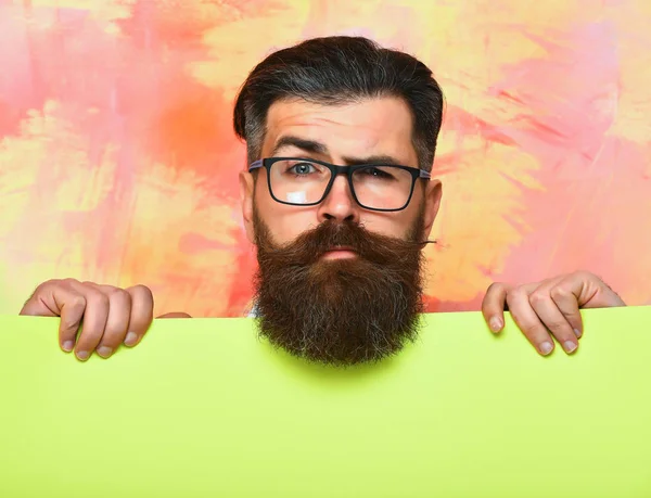 Szakállas férfi komoly arc szemüvegben színes háttér — Stock Fotó