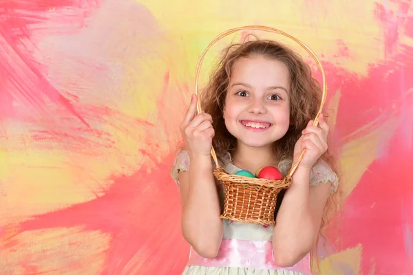 Boldog húsvéti lány tojással kosárban színes háttér — Stock Fotó