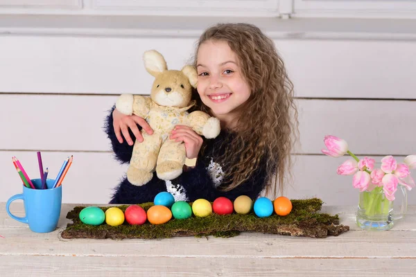 Chica feliz con juguete de conejo, lápiz, flores de tulipán, huevos de Pascua — Foto de Stock