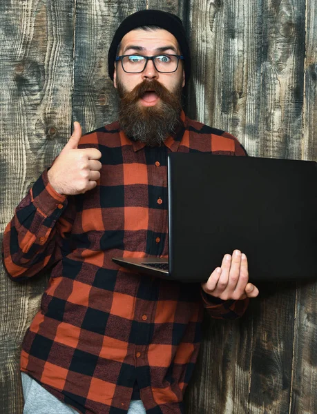 Bearded brutal caucasian hipster holding laptop — Stock Photo, Image