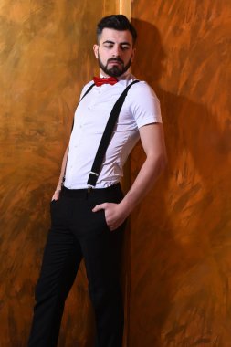 Stüdyo duvarında ciddi bir yüzü olan sakallı bir adam.