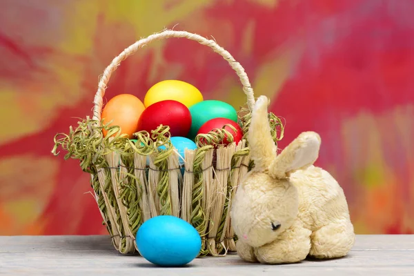 Voorjaar Pasen vakantie viering, kleurrijke eieren in een mand en konijn — Stockfoto
