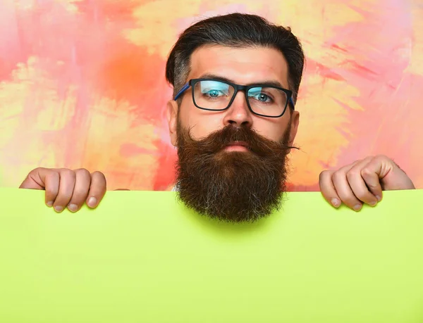 Uomo barbuto con volto serio in occhiali su sfondo colorato — Foto Stock