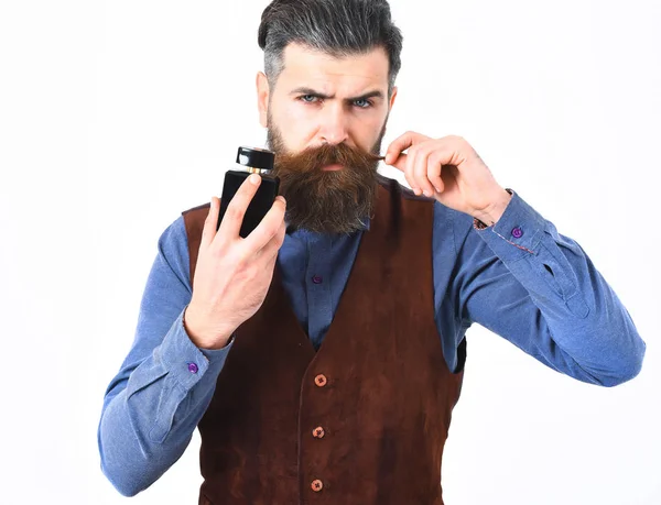 Бородатий чоловік тримає парфуми з серйозним обличчям — стокове фото