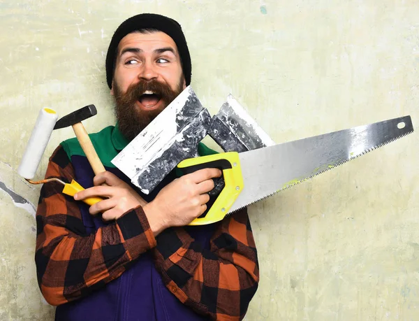 Бородатий чоловік тримає різні будівельні інструменти з щасливим обличчям — стокове фото