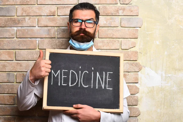 Barbudo brutal caucasiano médico segurando bordo com "Medicina" inscrição — Fotografia de Stock