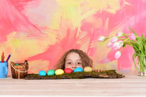 Glad påsk flicka med pennor, färgglada ägg och tulpan blommor — Stockfoto