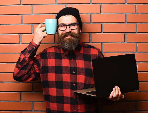 Baard brutale Kaukasische hipster holding laptop met beker — Stockfoto