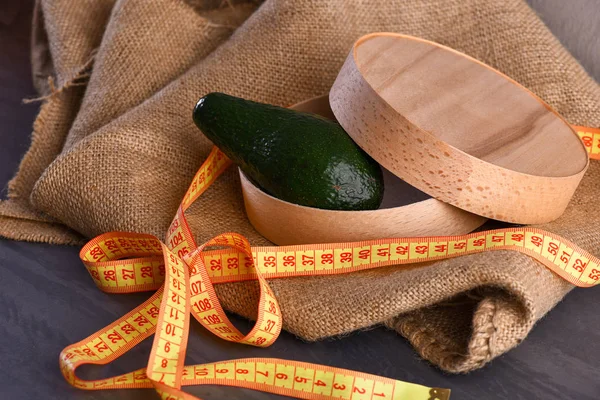Abacate em caixa de madeira em guardanapo de pano de saco com torneira de medição — Fotografia de Stock