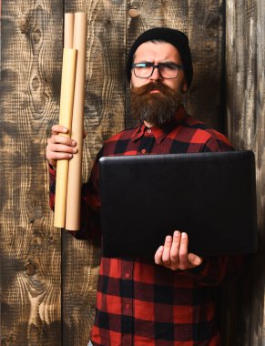 Kaba sakallı, beyaz tenli hippi elinde dizüstü bilgisayar ve el işi kâğıdı tutuyor.