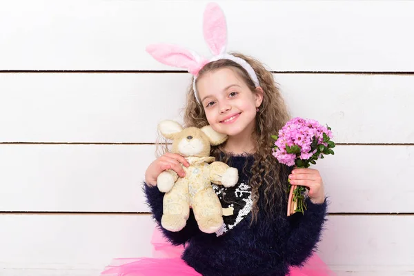 Lycklig flicka i kaninöron med påsk kanin leksak, blommor — Stockfoto