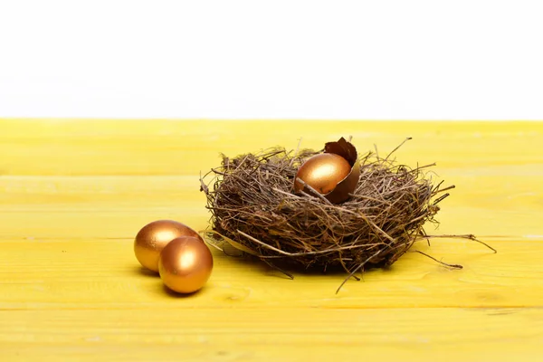 Разбитые пасхальные золотые яйца с скорлупой в птичьем гнезде — стоковое фото