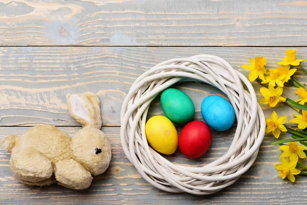 ウサギのおもちゃ黄色のナルシシズムと花輪のカラフルなイースターエッグ — ストック写真
