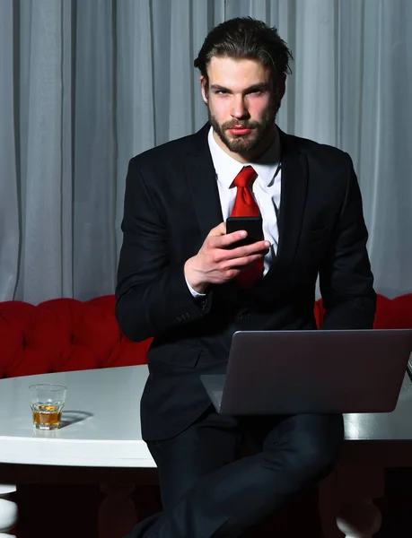Barbudo, hombre de negocios con vaso de whisky, teléfono celular, portátil — Foto de Stock