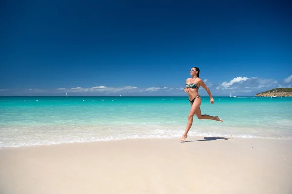 Mujer joven corriendo en la playa tropical — Foto de Stock