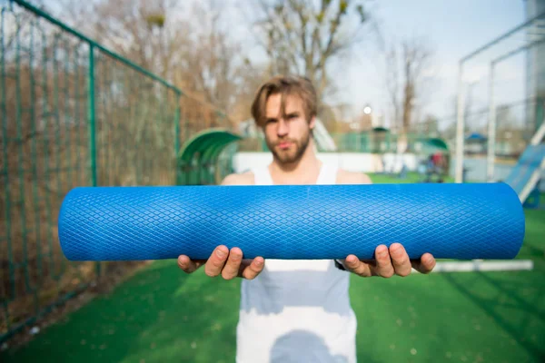 Yoga, colchoneta de fitness color azul en manos de hombre musculoso —  Fotos de Stock