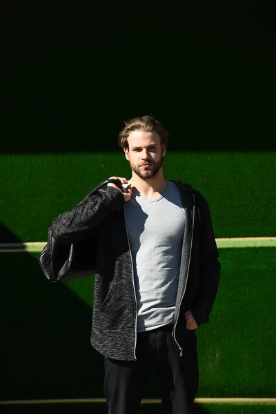 Fuerte deportista con bolsa de cuero deportivo sobre un fondo verde — Foto de Stock