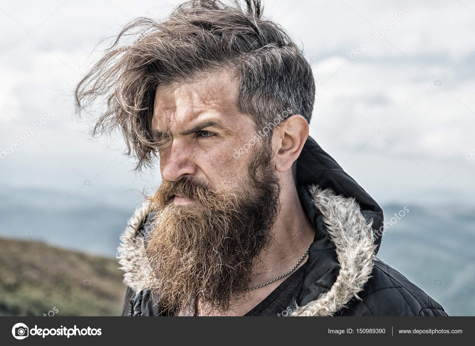 Hipster, hombre barbudo en la cima de la montaña en el cielo