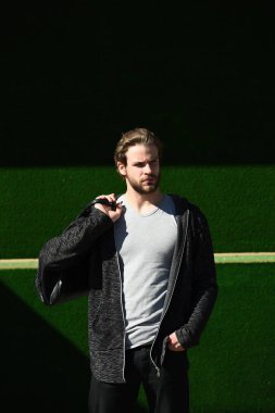 Yeşil arka planda spor çantalı bir adam.