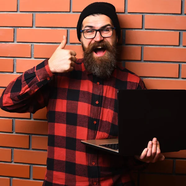 Bearded brutal caucasian hipster holding laptop — Stock Photo, Image