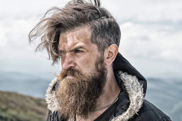 Hipster, hombre barbudo en la cima de la montaña en el cielo nublado natural —  Fotos de Stock