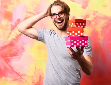 Beyaz sakallı seksi maço adam elinde hediye kutuları tutuyor.