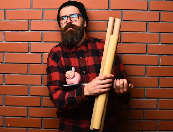 Bearded caucasian hipster holding laptop, piggy bank and craft paper — Stock Photo, Image