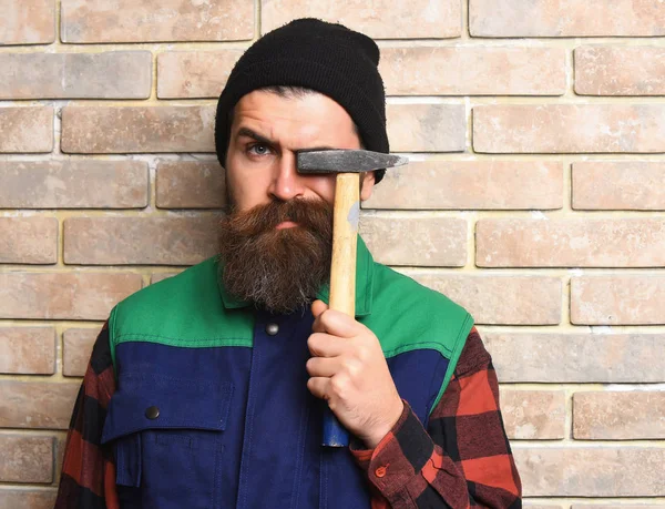Бородатый рабочий держит молоток серьезное лицо — стоковое фото