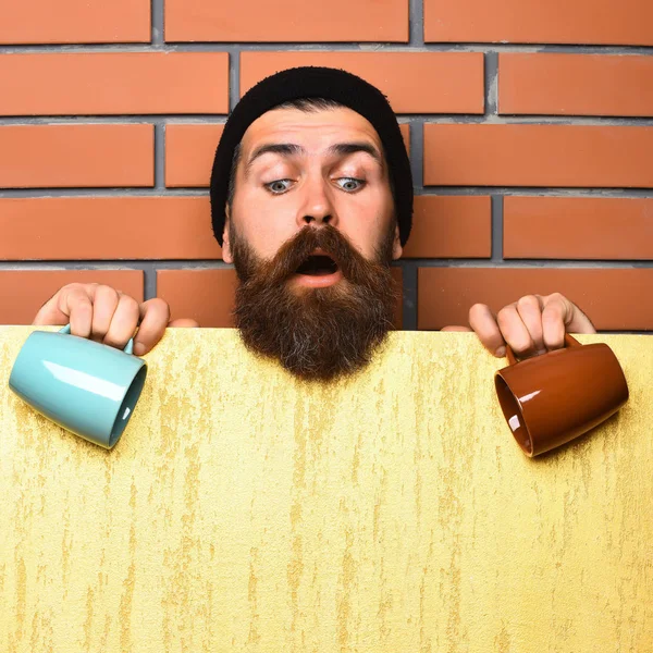 Barbudo brutal hipster caucásico con hoja de papel y tazas —  Fotos de Stock