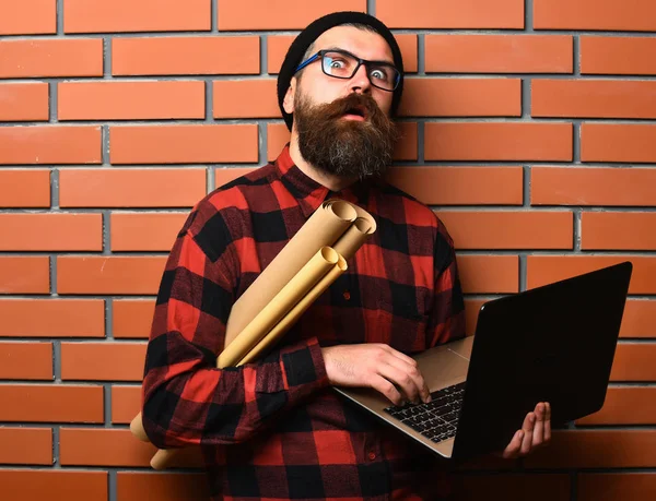 Szakállas brutális kaukázusi hipster gazdaság laptop és kézműves papír — Stock Fotó