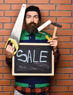 Sakallı işçi elinde çeşitli yapı aletleri ve yiyecek, şaşırmış yüz.