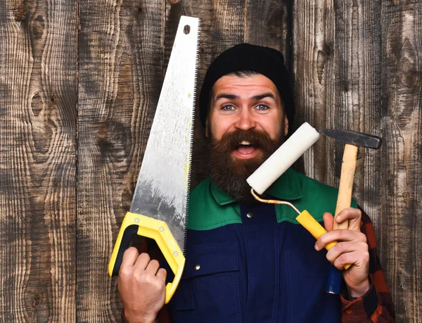 Bebaarde bouwer houden verschillende gebouw tools met blij gezicht — Stockfoto