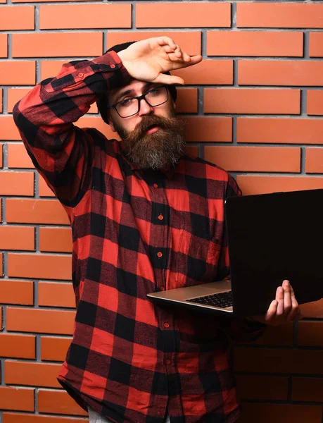 Bearded brutal caucasian hipster holding laptop — Stock Photo, Image