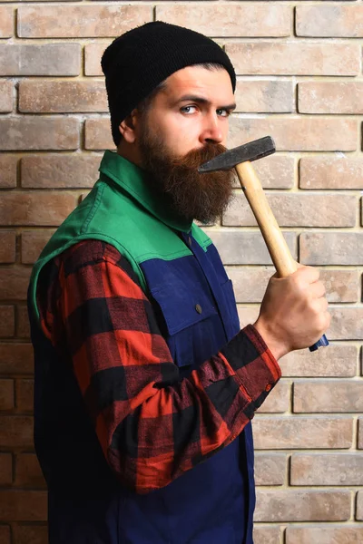 Vousatý stavitel muž drží kladivo vážný obličej — Stock fotografie