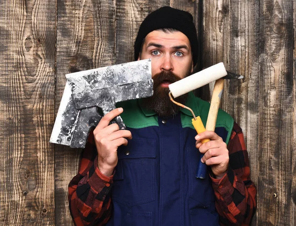 Bärtiger Bauarbeiter mit verschiedenen Bauwerkzeugen und überraschtem Gesicht — Stockfoto