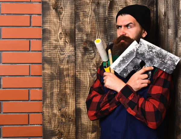 Бородатий майстер тримає різні будівельні інструменти з серйозним обличчям — стокове фото