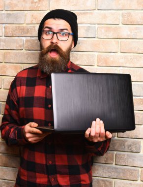 Kaba sakallı, beyaz tenli hippi dizüstü bilgisayar tutuyor.