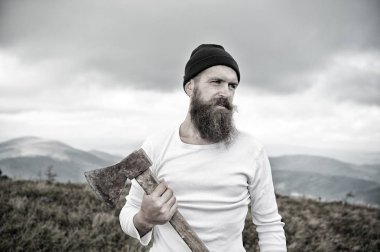 sakallı adam, bulutlu gökyüzü ile dağ üst balta tutar