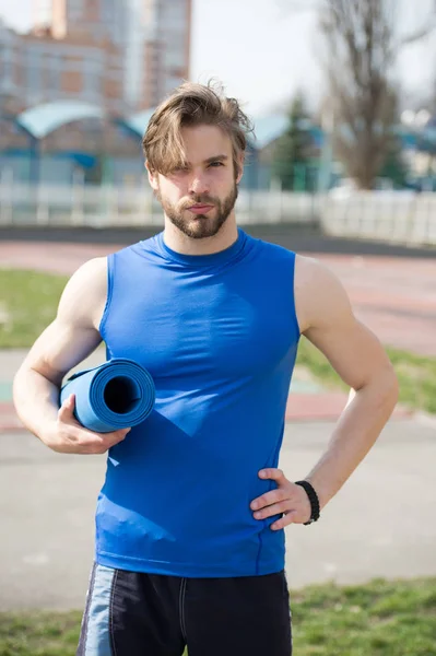 Homem muscular segurando ioga ou tapete de fitness para o exercício — Fotografia de Stock