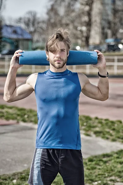 Yoga, colchoneta de fitness color azul en manos de hombre musculoso —  Fotos de Stock