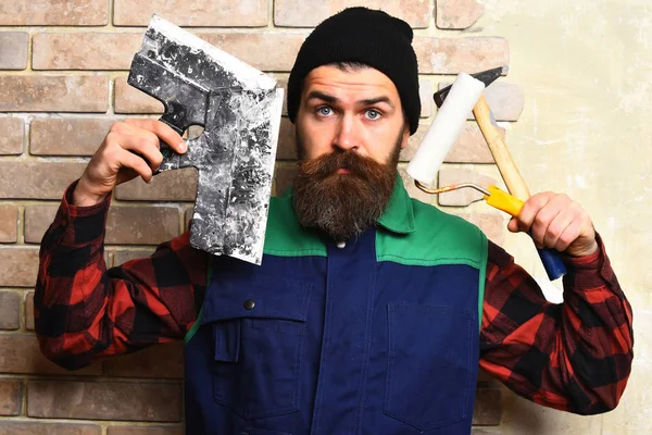 Bearded builder man holding various building tools with serious face — Stock Photo, Image
