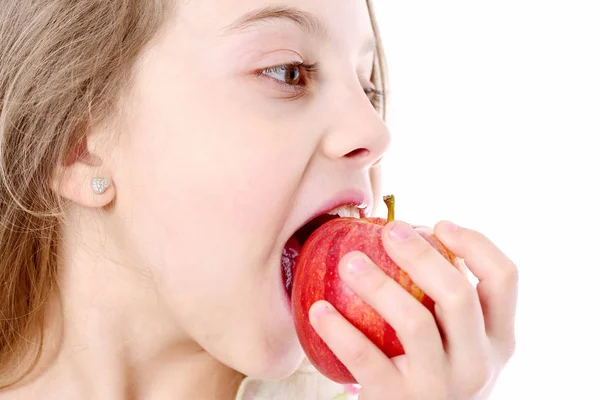Милая маленькая девочка ест яблоко на белом фоне — стоковое фото
