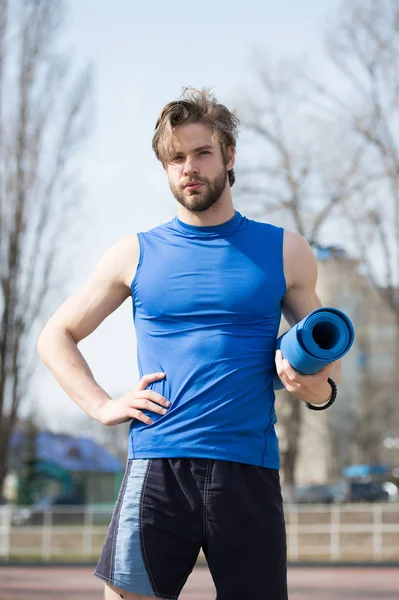 Muskularny mężczyzna trzyma mat joga lub fitness do ćwiczeń — Zdjęcie stockowe