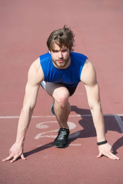 Atlético barbudo hombre con cuerpo muscular estiramiento en pista de atletismo — Foto de Stock