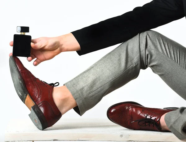 Starka manliga ben och handhållen parfym på träbänk — Stockfoto